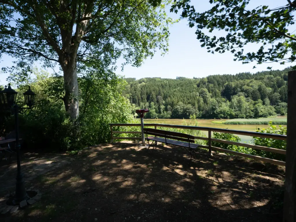 Schattiger Aussichtsplatz unter einer Birke, Geländer und Blick auf den Fluss