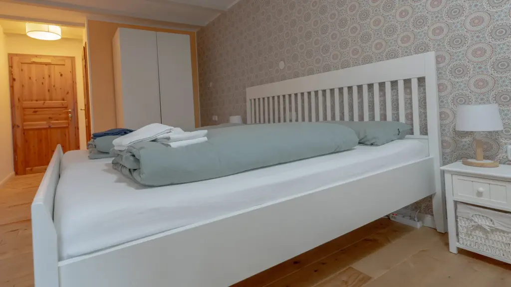 Zimmer 2: Doppelbett mit Nachttischen und Blick zur Tür
