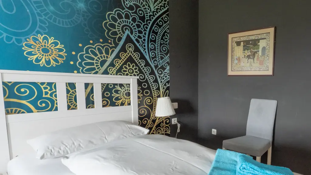 Zimmer 3: Bettkopfteil vor Mandala-Wand mit Wandbild