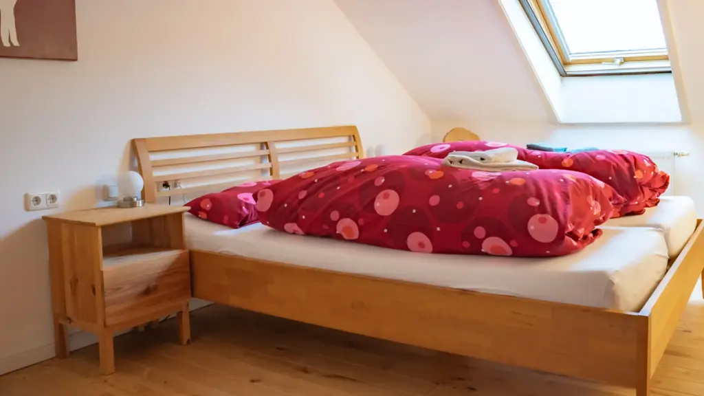 Zimmer 6: Doppelbett mit roter Bettwäsche unter dem Dachfenster